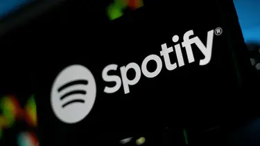 Логотип Spotify: белый круг с тремя линиями и надпись на темном фоне.