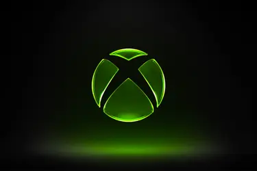 Светящийся зеленый логотип Xbox на черном фоне.