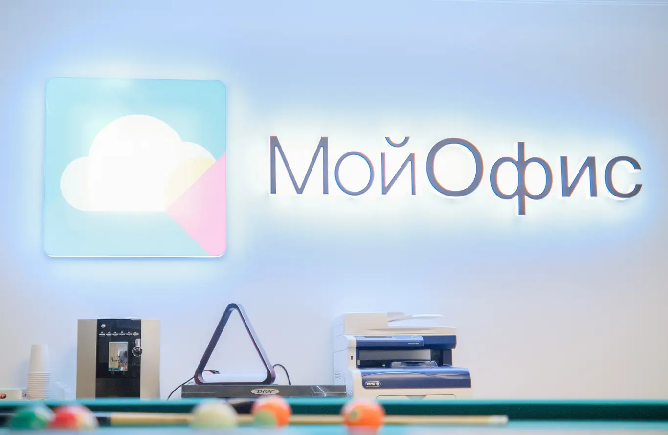 На изображении представлен логотип МойОфис на фоне стены.