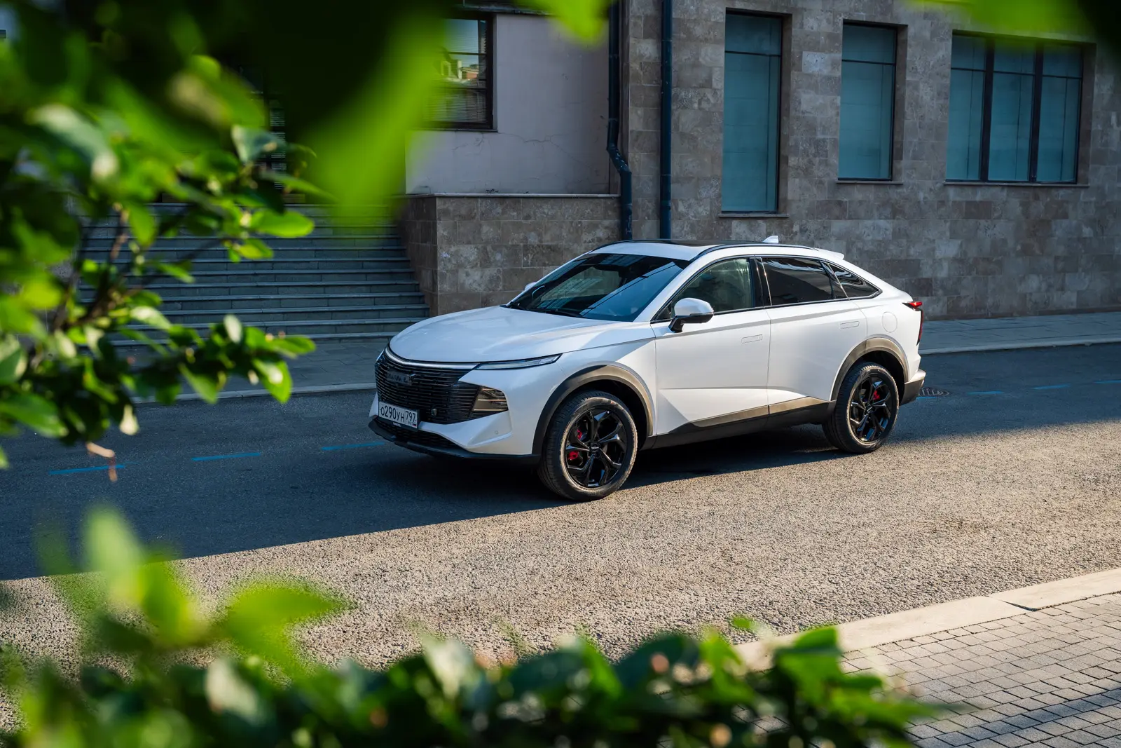 Белый автомобиль Haval F7x, припаркованный на дороге рядом с зданием.