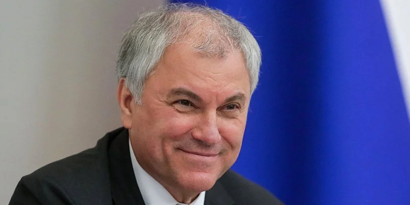 Мужчина средних лет в деловом костюме, улыбается.