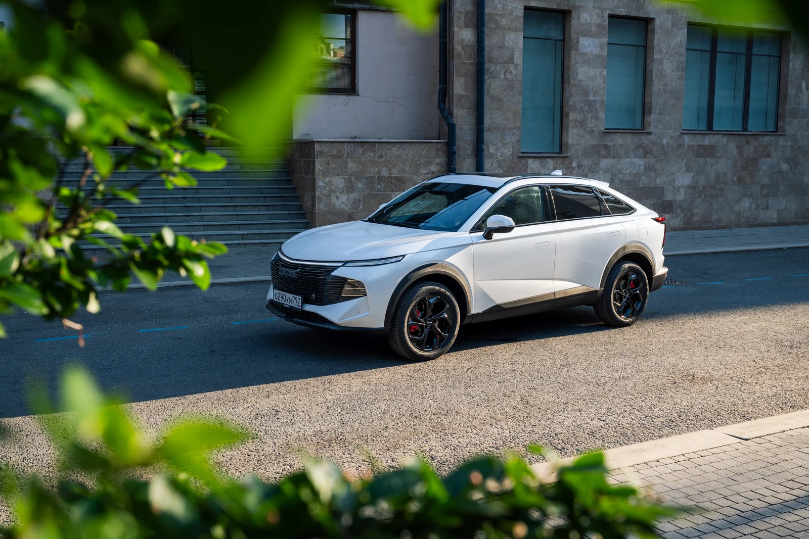 Белый автомобиль Haval F7x, припаркованный на дороге рядом с зданием.
