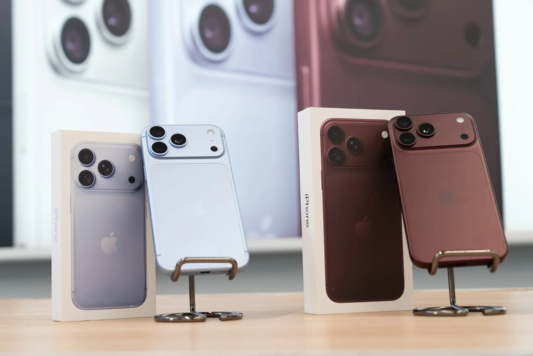 Четыре смартфона iPhone на подставках у коробок, на заднем плане изображения камер.