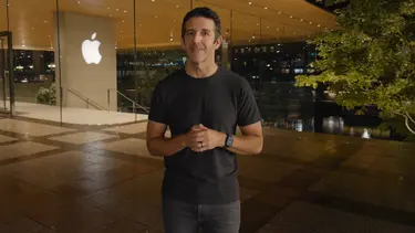 Мужчина в черной футболке, стоящий у входа в магазин Apple.