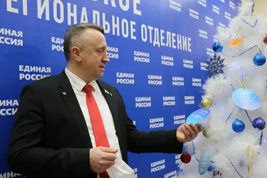 Мужчина в костюме держит елочную игрушку