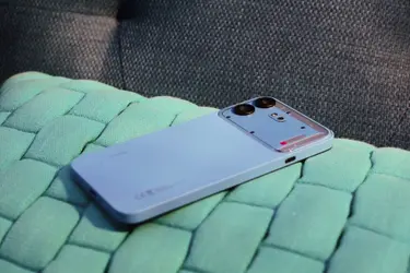 Смартфон Nothing Phone (4b) синего цвета на зеленой плетеной поверхности.
