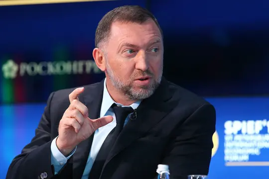 Мужчина средних лет в деловом костюме выступает на конференции.