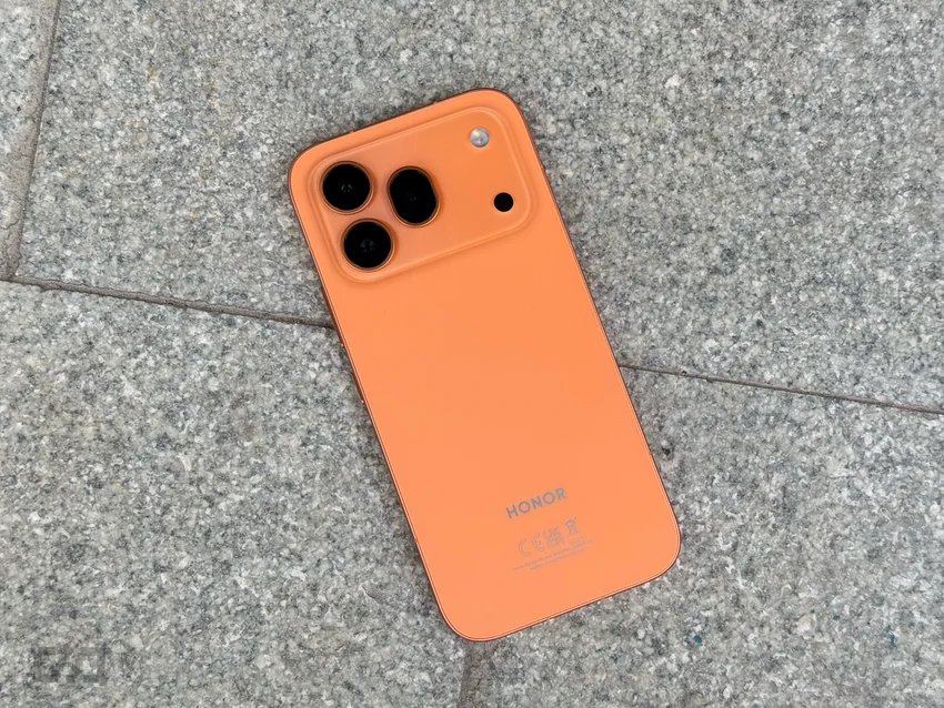 Оранжевый смартфон Honor 600 Pro с тройной камерой на сером камне.