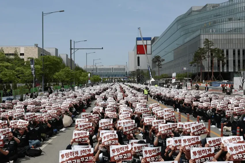 На фотографии запечатлен митинг с участием множества людей, держащих плакаты с текстом на корейском языке.