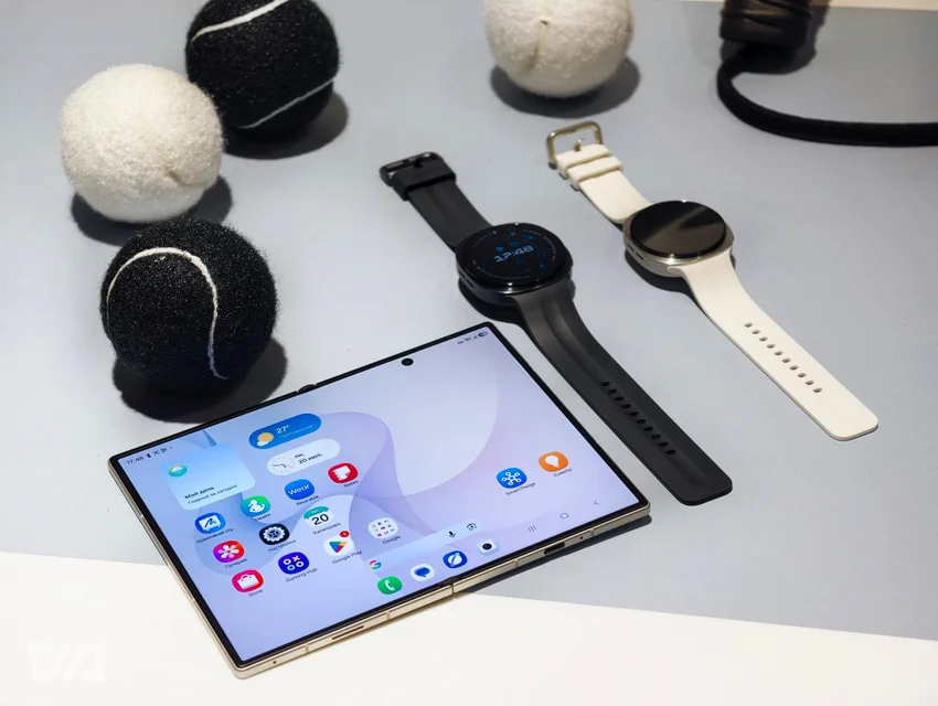 Складной смартфон Samsung, два умных часа и теннисные мячи на столе.