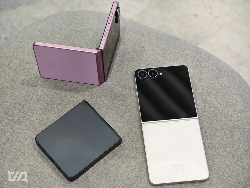 Три складных смартфона Samsung разных цветов (фиолетовый, черный, белый) на сером пуфе.
