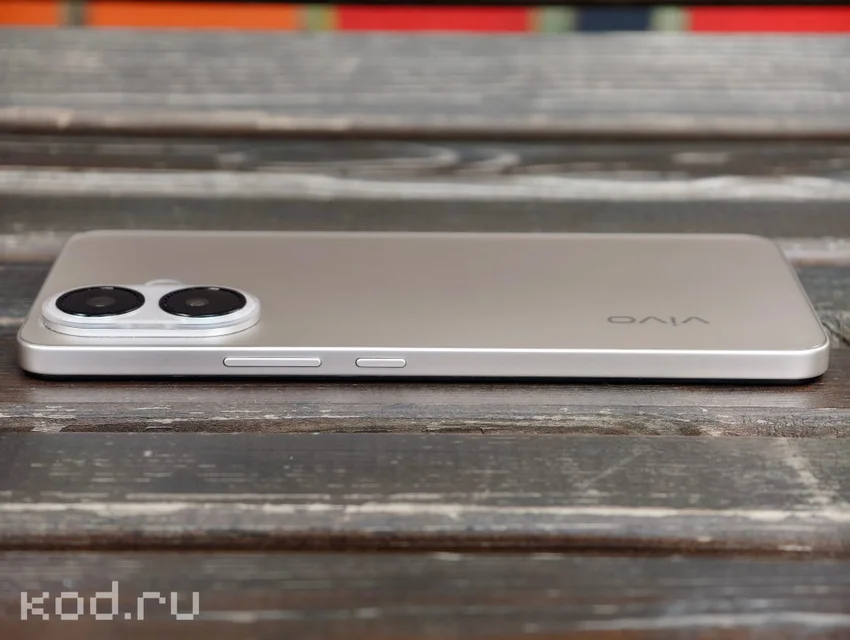 Золотой смартфон vivo V70 Lite 5G с двумя камерами на деревянной поверхности.