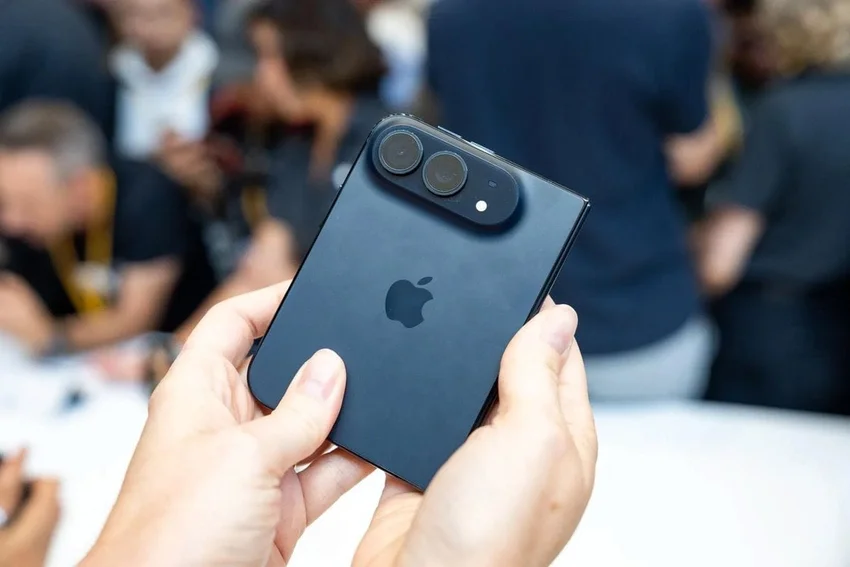 Руки держат сложенный смартфон Apple с двумя камерами и логотипом на задней панели.