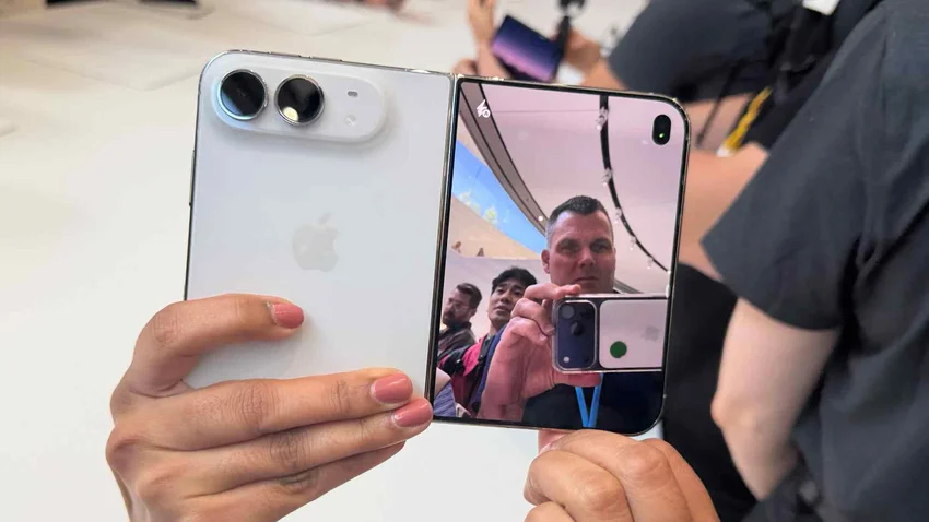 Раскрытый белый iPhone Duo с двумя камерами на задней панели в руках.
